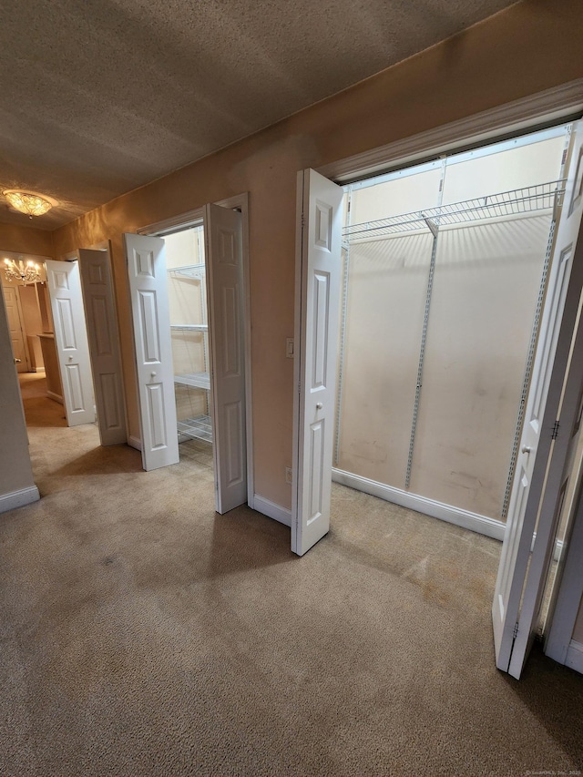 unfurnished bedroom with a chandelier, baseboards, a textured ceiling, and carpet