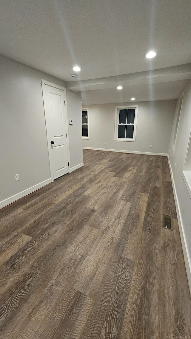 empty room featuring visible vents, baseboards, and dark wood-type flooring