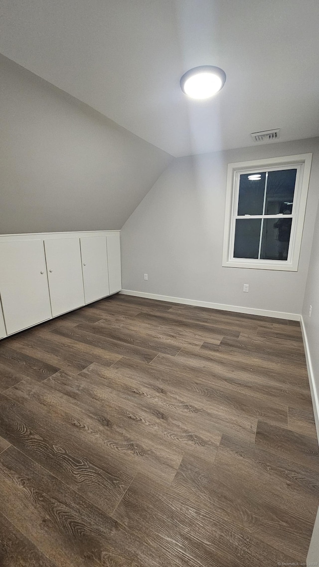 bonus room with lofted ceiling, dark wood-style floors, visible vents, and baseboards