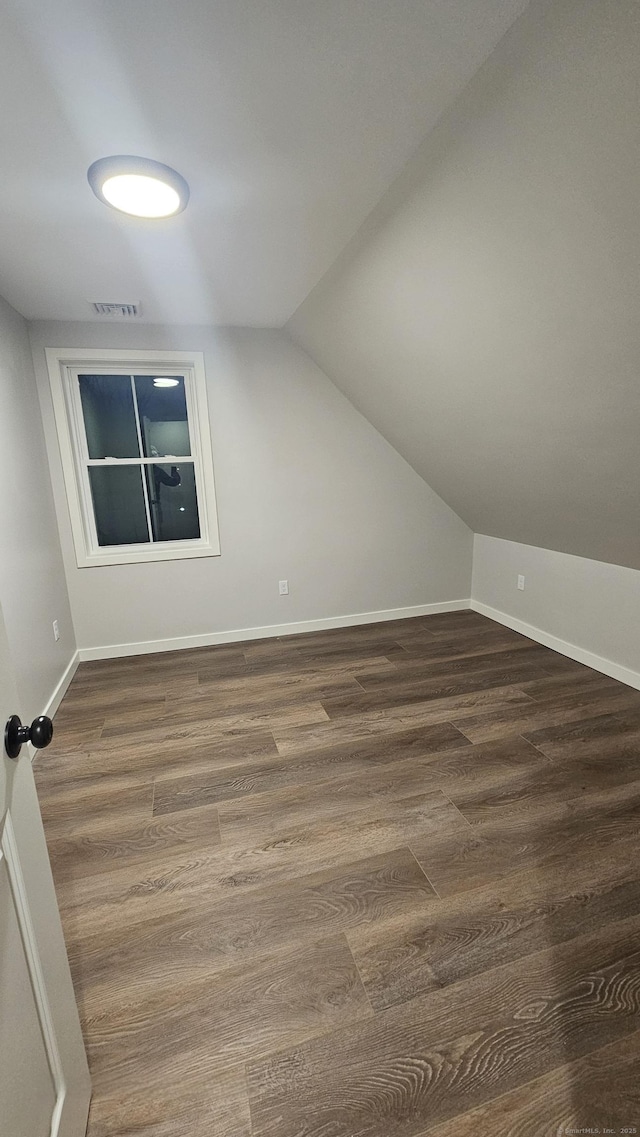 bonus room featuring dark wood finished floors, lofted ceiling, baseboards, and visible vents