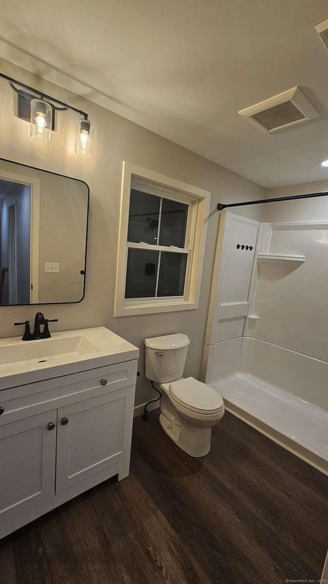 full bathroom featuring vanity, wood finished floors, visible vents, walk in shower, and toilet