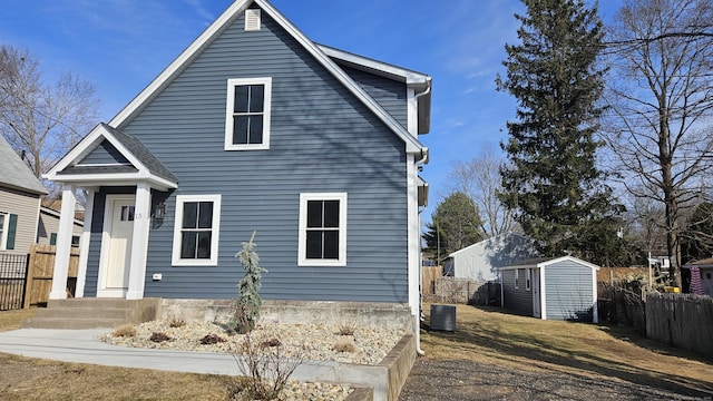 view of front facade with a storage shed, central AC, an outdoor structure, and fence