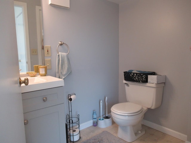 bathroom with toilet, vanity, and baseboards