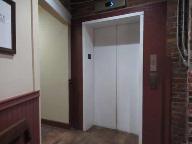 corridor with elevator and wood finished floors