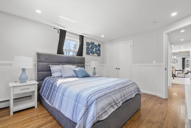 bedroom featuring recessed lighting, a closet, hardwood / wood-style floors, and a baseboard radiator