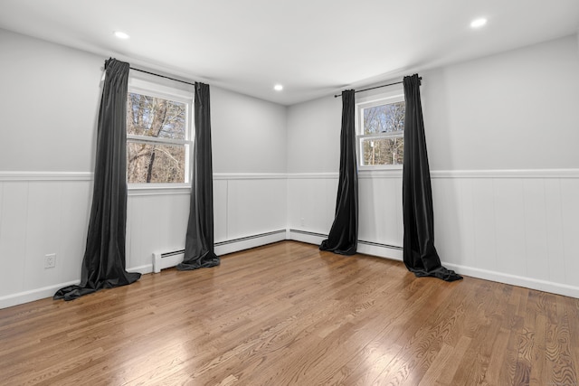 empty room featuring a wainscoted wall, recessed lighting, a baseboard heating unit, and wood finished floors