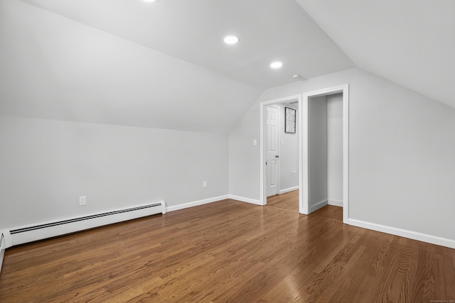 additional living space featuring vaulted ceiling, wood finished floors, baseboards, and a baseboard radiator