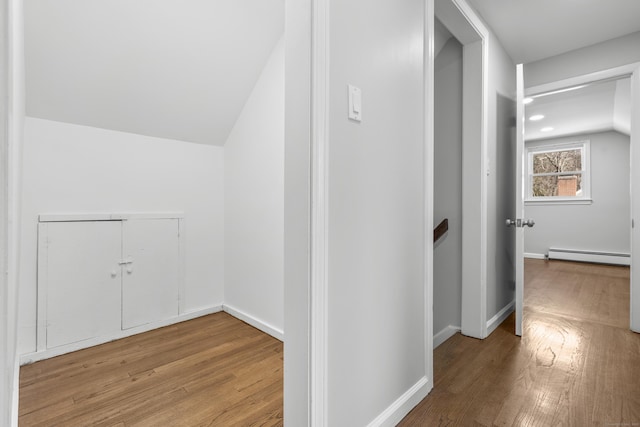 corridor with hardwood / wood-style flooring, baseboards, lofted ceiling, and a baseboard radiator