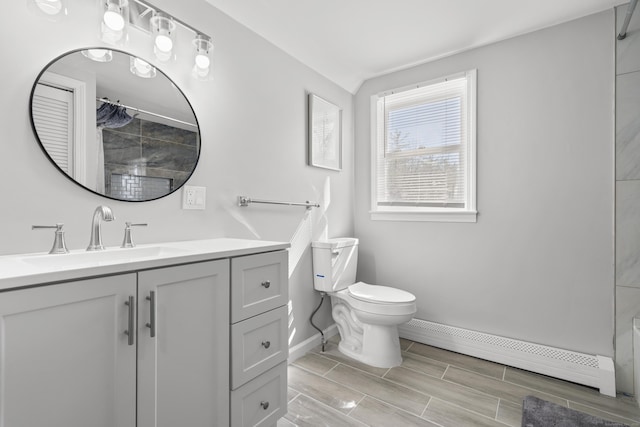 bathroom with vanity, baseboards, wood tiled floor, a baseboard heating unit, and toilet