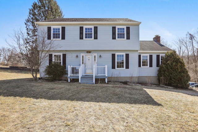 colonial home with a chimney and a front yard