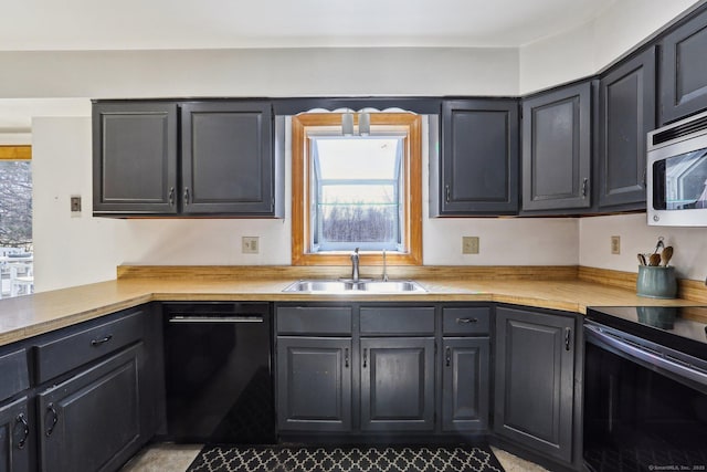 kitchen featuring a wealth of natural light, black appliances, light countertops, and a sink