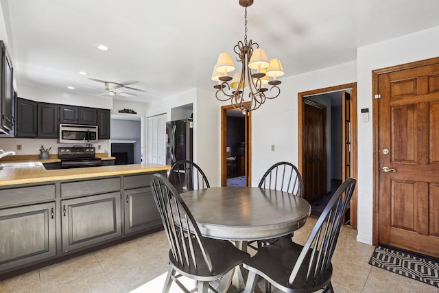 dining area with light tile patterned floors, ceiling fan with notable chandelier, and recessed lighting