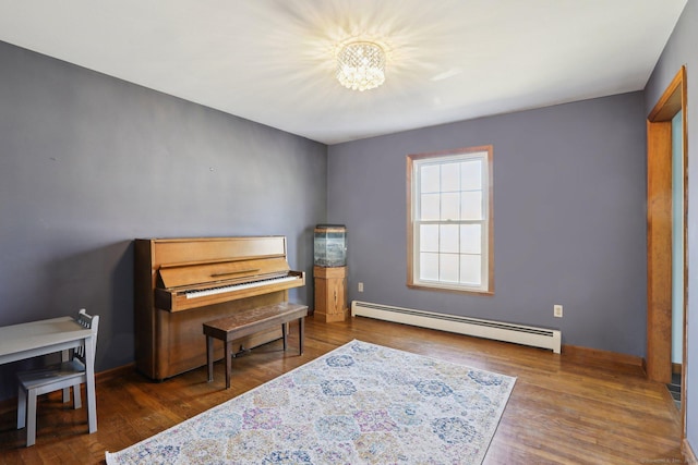 living area with a baseboard radiator, baseboards, an inviting chandelier, and wood finished floors