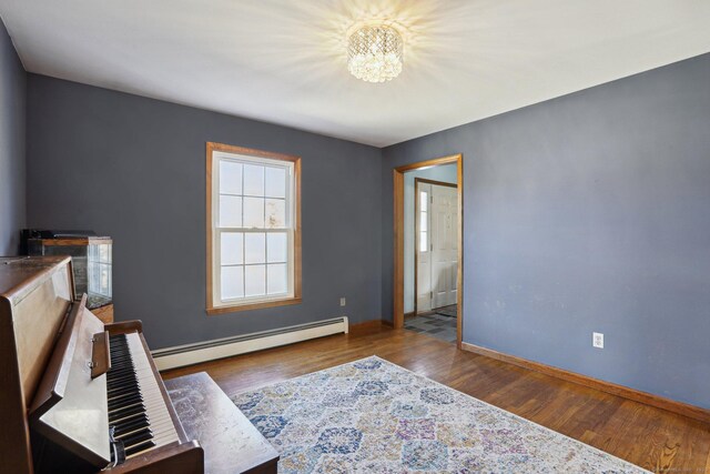 interior space with a baseboard heating unit, an inviting chandelier, wood finished floors, and baseboards