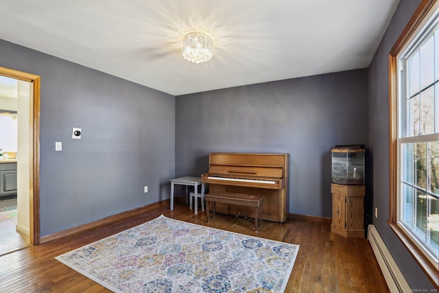 living area with an inviting chandelier, hardwood / wood-style flooring, baseboards, and a baseboard radiator
