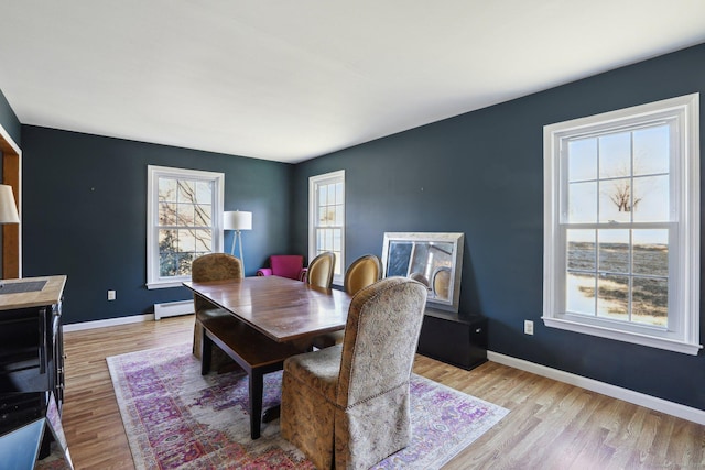 dining room with a baseboard heating unit, wood finished floors, and baseboards
