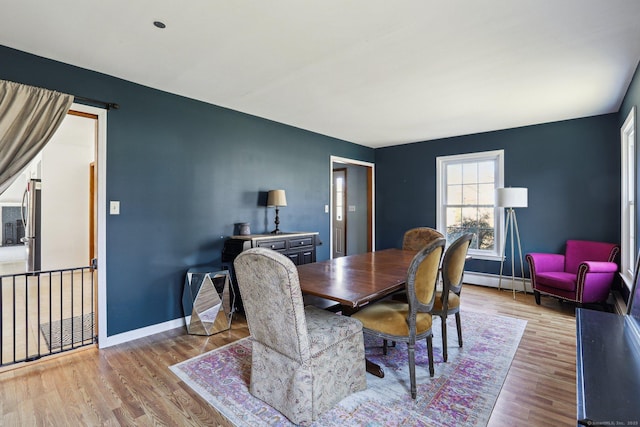 dining space featuring wood finished floors, baseboards, and a baseboard radiator