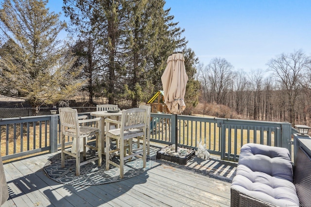 deck featuring a playground and outdoor dining area