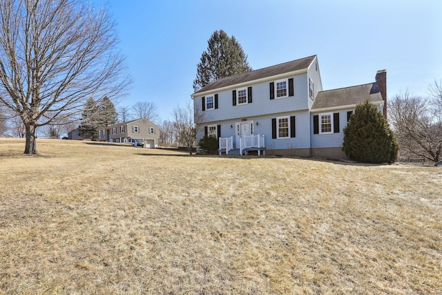 colonial home featuring a front yard and a chimney