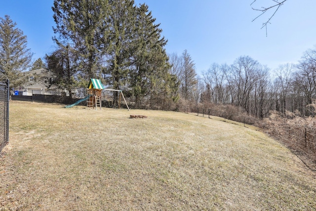 view of yard with a playground, fence, and an outdoor fire pit
