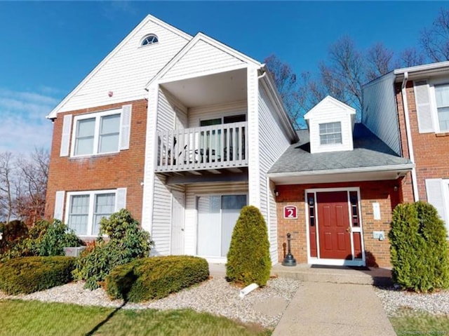 view of property with brick siding and a balcony