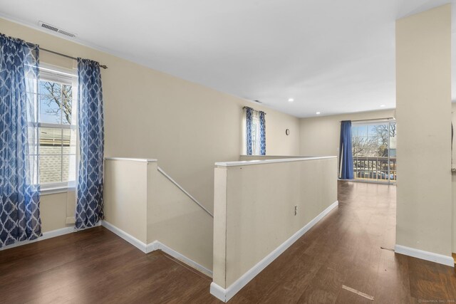 corridor featuring visible vents, an upstairs landing, baseboards, and wood finished floors