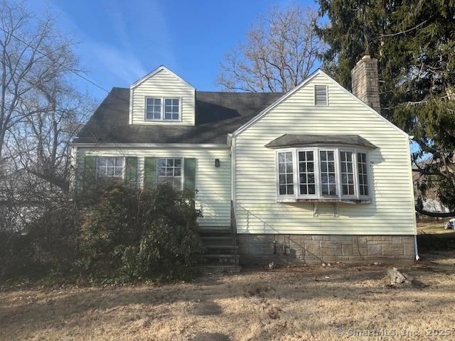 view of side of home featuring a chimney and entry steps