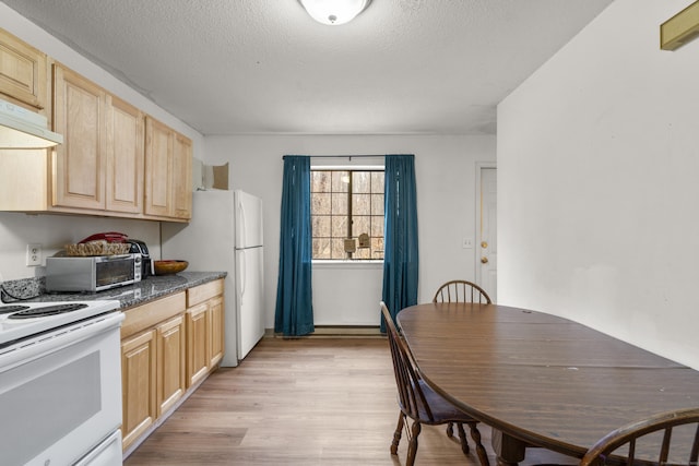 kitchen with light brown cabinetry, under cabinet range hood, dark countertops, white appliances, and light wood-style floors