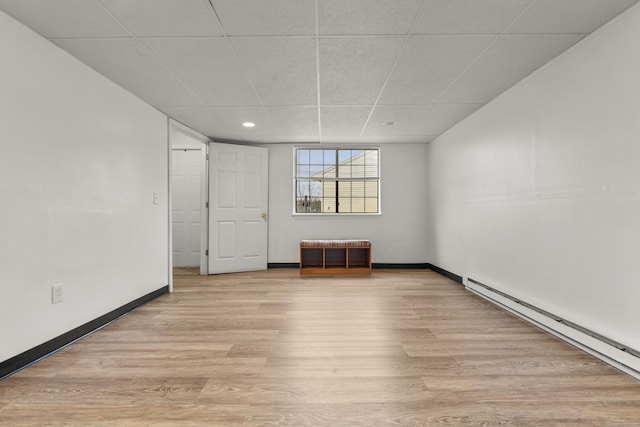 empty room featuring light wood finished floors, baseboards, and baseboard heating