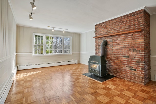 unfurnished living room with a baseboard radiator, a wood stove, rail lighting, crown molding, and baseboard heating