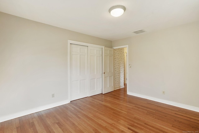 unfurnished bedroom featuring a closet, visible vents, baseboards, and light wood-style floors