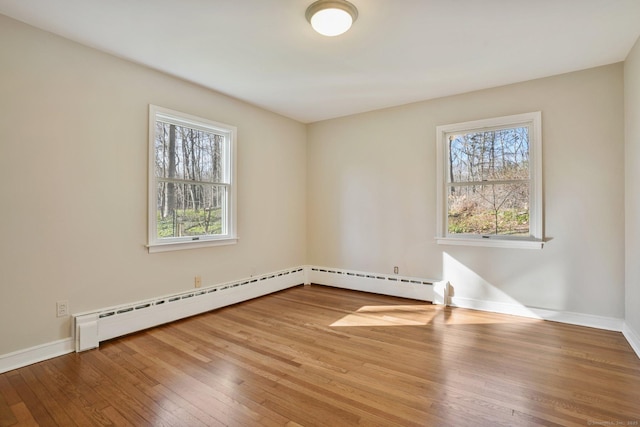 unfurnished room featuring a wealth of natural light, baseboards, and wood-type flooring