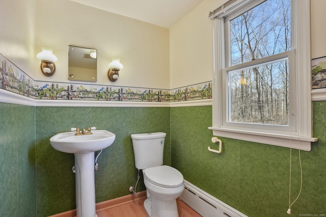 bathroom with wallpapered walls, toilet, wood finished floors, and baseboards