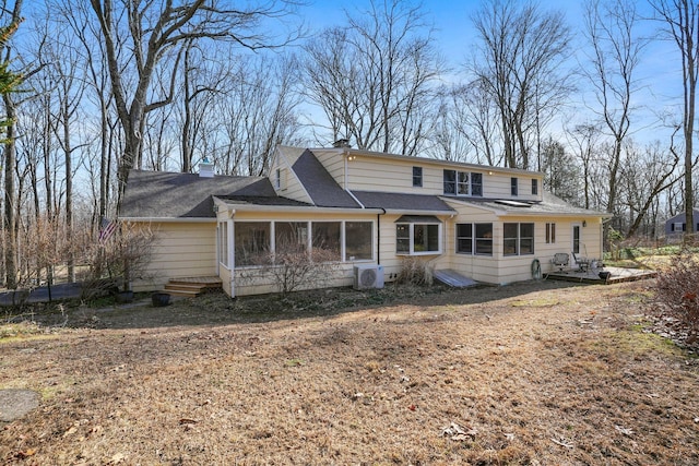 rear view of property with a shingled roof, ac unit, a sunroom, and a chimney