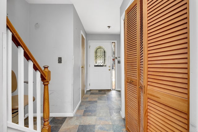 foyer entrance with stone finish flooring, baseboards, and stairs