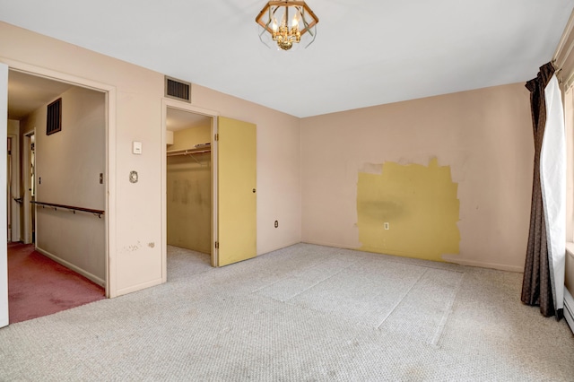 unfurnished bedroom with visible vents, carpet floors, an inviting chandelier, and a closet