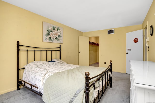 bedroom with visible vents, light carpet, baseboards, and a walk in closet