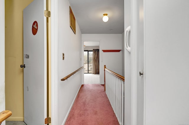 hall with baseboards, an upstairs landing, and carpet flooring