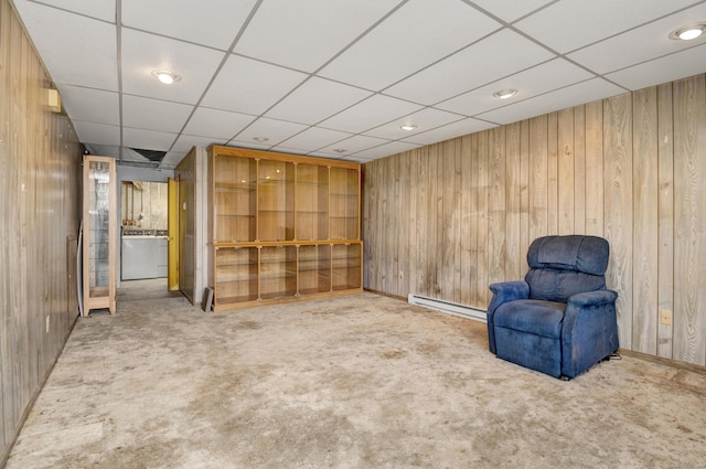 unfurnished room with carpet flooring, wood walls, and a baseboard heating unit