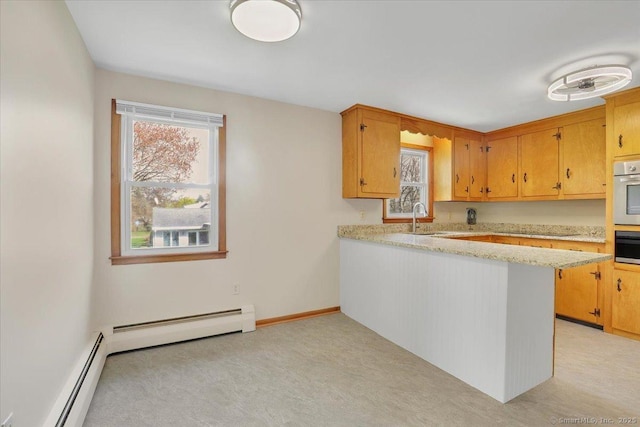 kitchen with a peninsula, stainless steel oven, a baseboard heating unit, and a sink