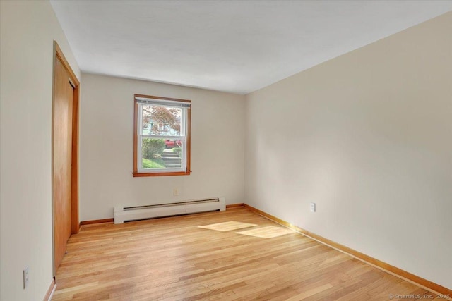 unfurnished bedroom featuring baseboards, a closet, light wood finished floors, and a baseboard radiator