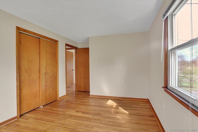 unfurnished bedroom with baseboards, light wood-style floors, and a closet