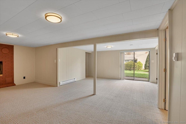 below grade area featuring light carpet, a brick fireplace, and a baseboard radiator
