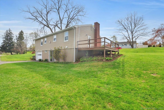 view of side of home featuring a chimney, a yard, a wooden deck, driveway, and an attached garage