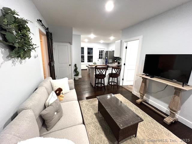 living room featuring a barn door, baseboards, and wood finished floors