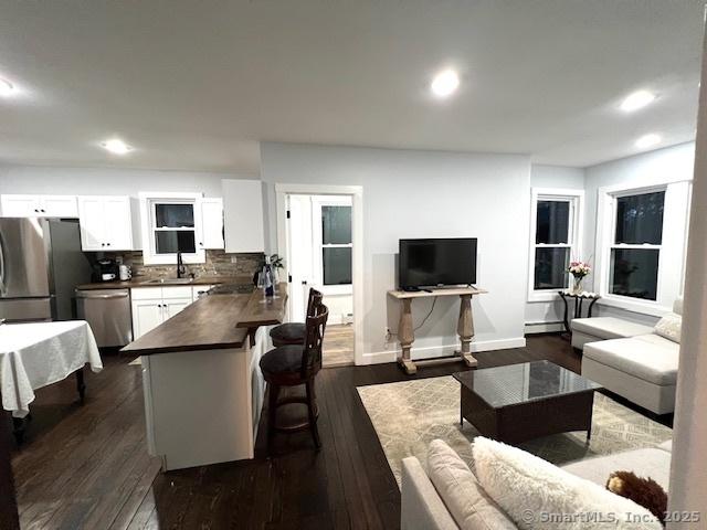 living room with recessed lighting, a baseboard radiator, baseboards, and dark wood-style floors