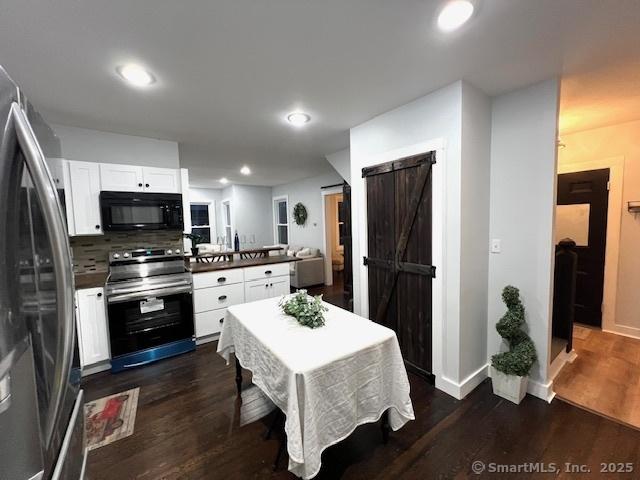 kitchen featuring white cabinetry, a barn door, dark wood-style floors, and stainless steel appliances