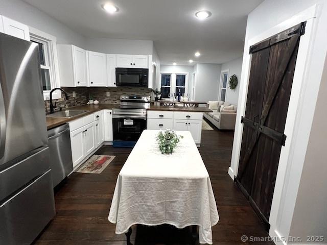 kitchen featuring white cabinets, appliances with stainless steel finishes, a barn door, and a sink