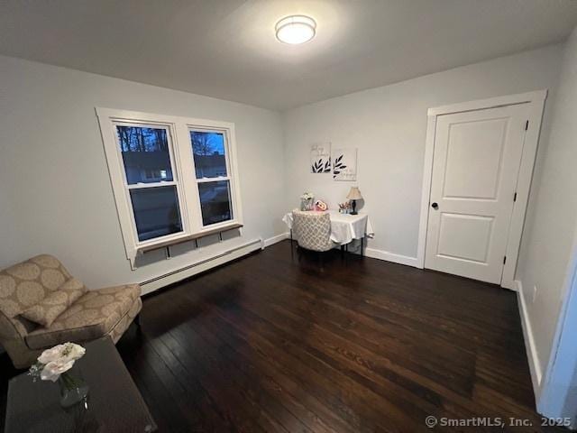 unfurnished room with a baseboard heating unit, dark wood-style floors, and baseboards