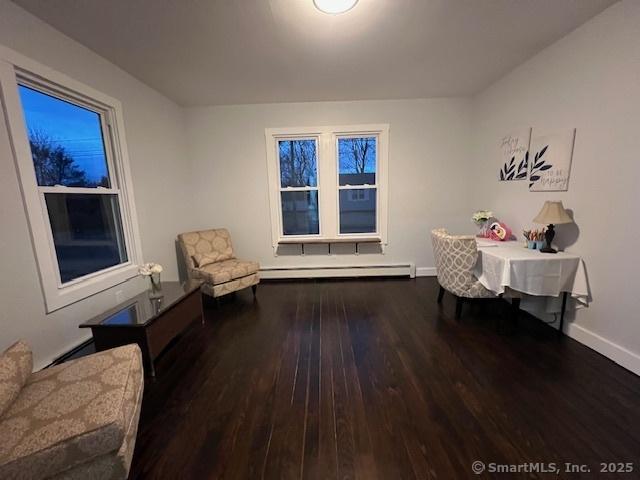 living area featuring a baseboard heating unit, baseboards, and wood finished floors